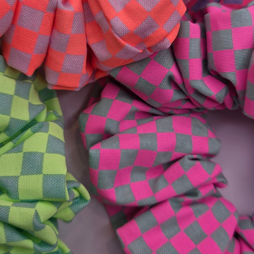 Checkered scrunchies in pink, green, and orange on a gray background