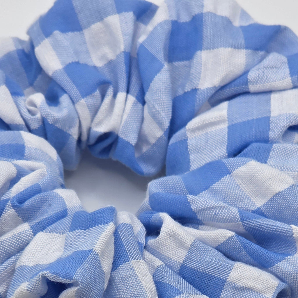 A fabric hair scrunchie with a blue and white gingham checkered pattern, photographed on a plain white background.