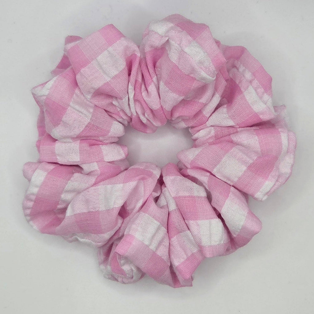 A fabric hair scrunchie with a pink and white gingham checkered pattern, photographed on a plain white background.