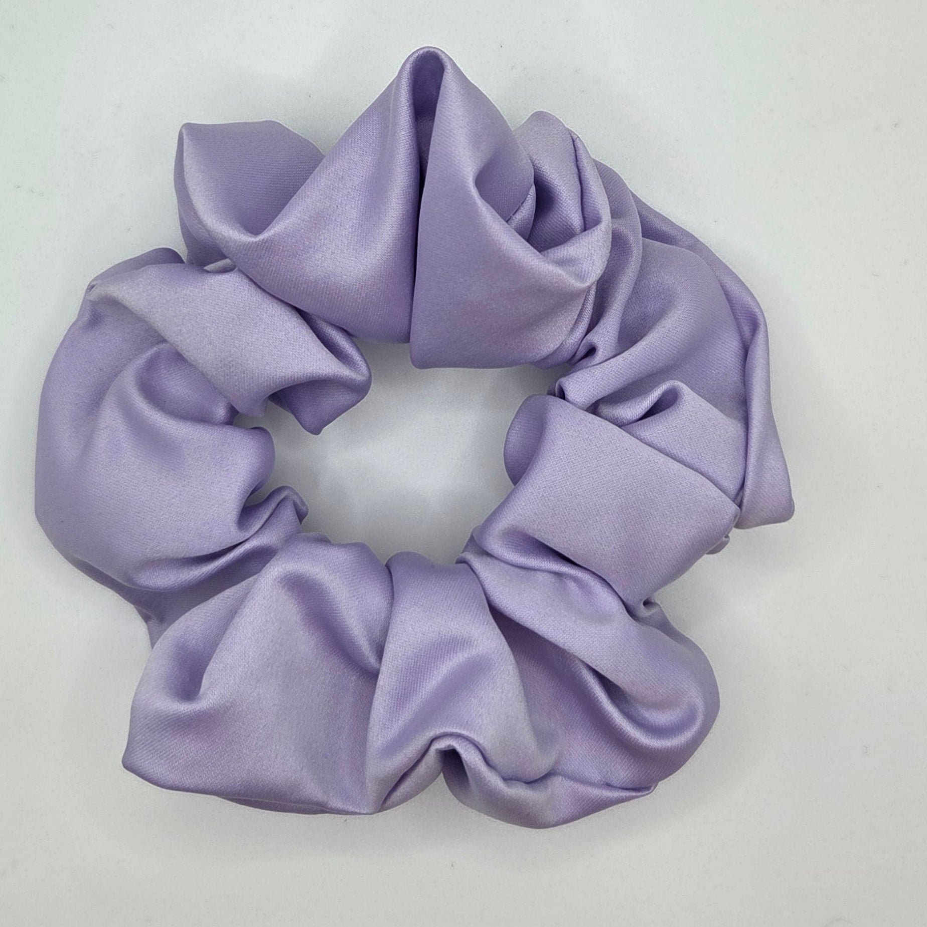 A lavender purple satin scrunchie on a plain white background.