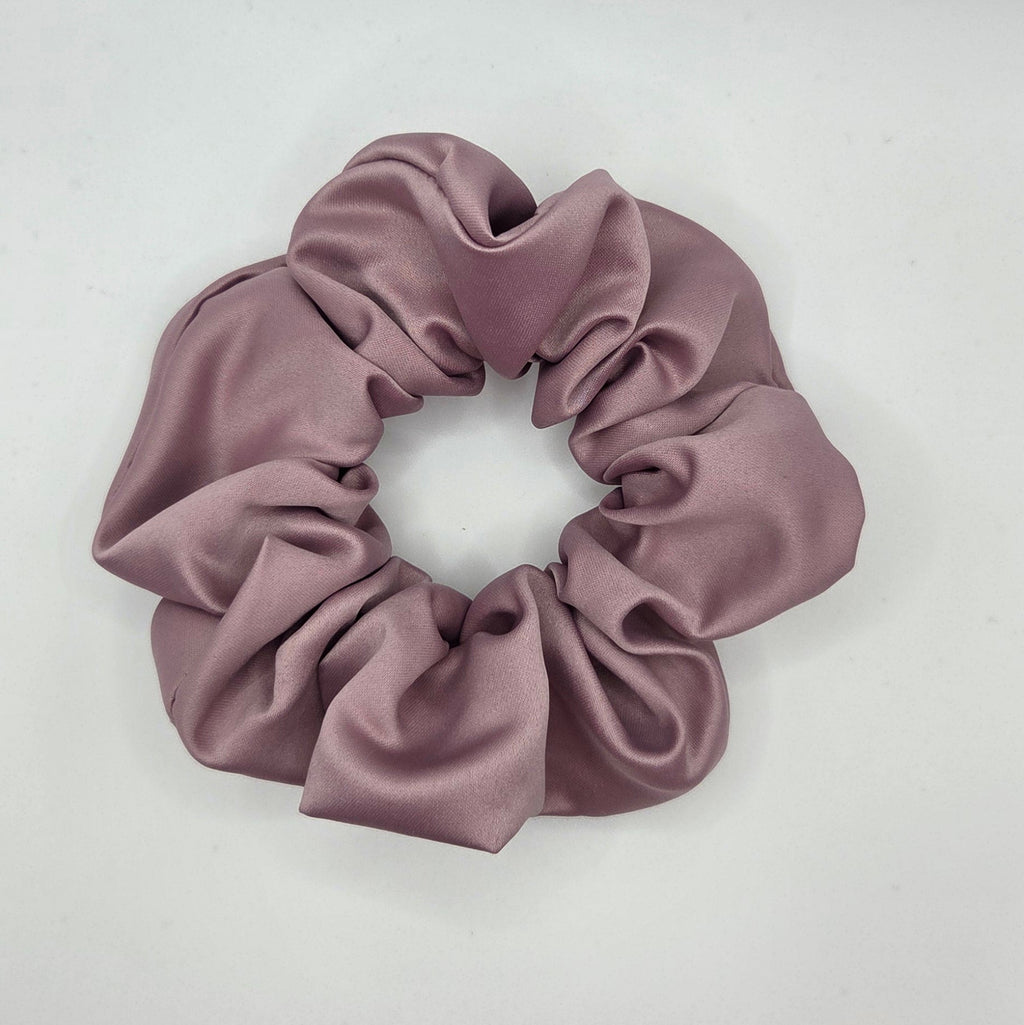 A dusty mauve satin hair scrunchie displayed on a plain white surface.