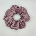 A dusty mauve satin hair scrunchie displayed on a plain white surface.