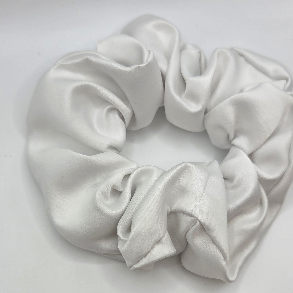 A white satin hair scrunchie with a soft, lustrous sheen, photographed on a plain light gray background.